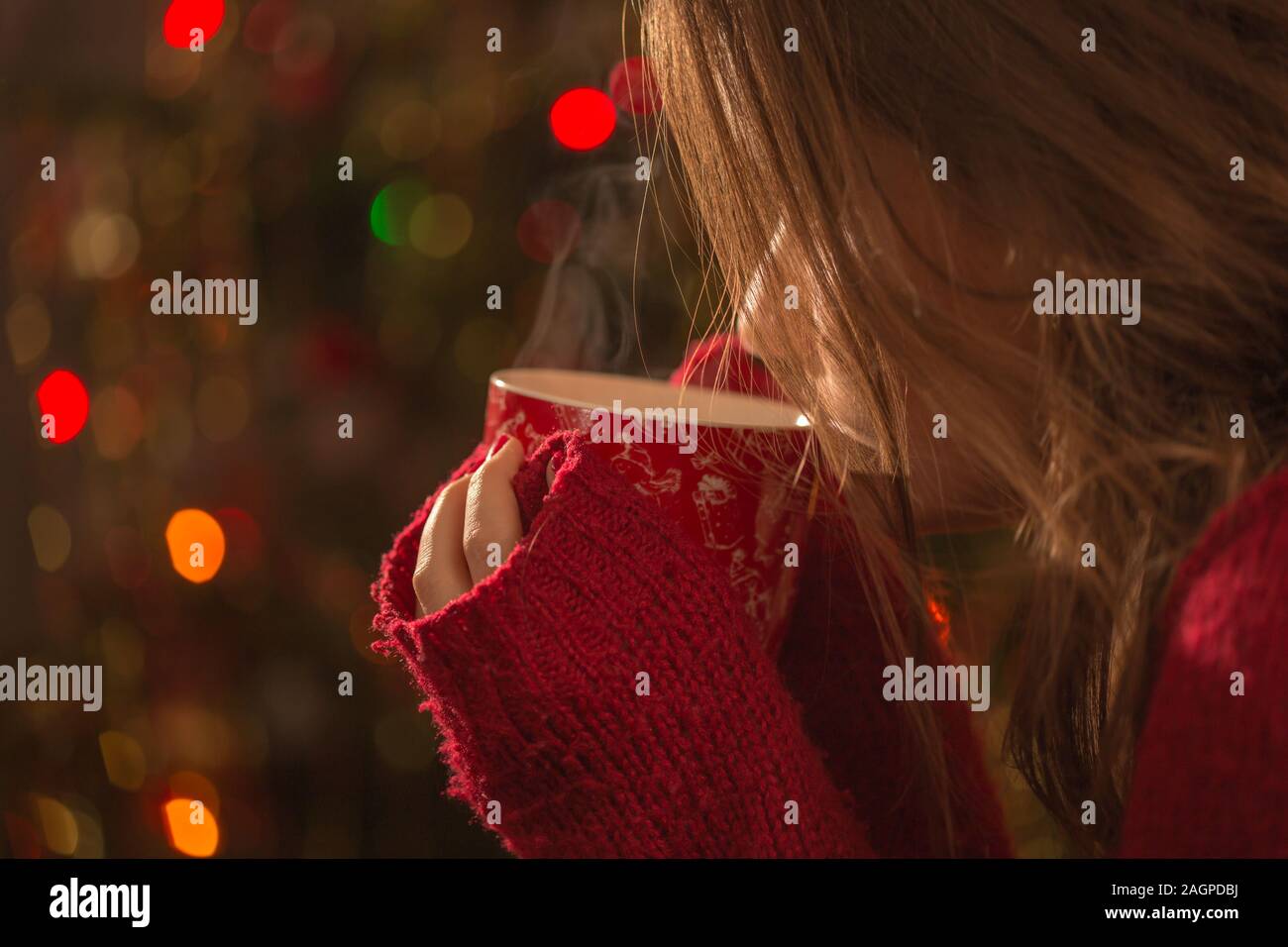 Jeune femme avec une tasse de chocolat chaud ou de thé ou de café en face de l'arbre de Noël. Noël et de détente concept. Banque D'Images