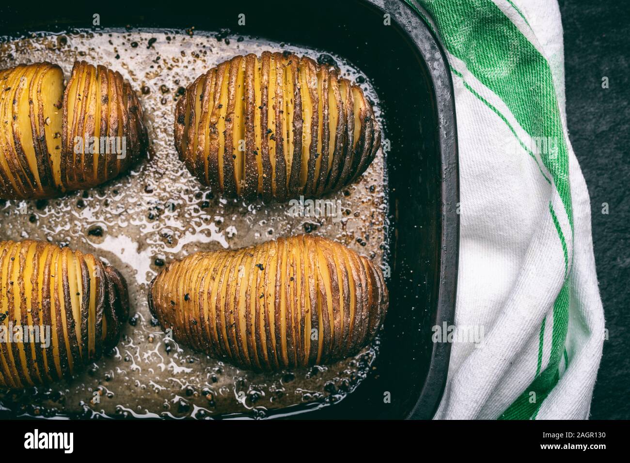 Hasselback Pommes de terre avec le beurre fondu, le sel et le poivre dans une rôtissoire, déposer le bac Banque D'Images