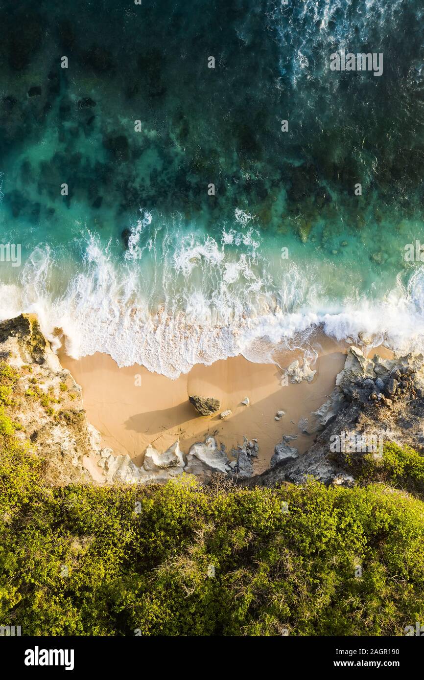 Vue de dessus, superbe vue aérienne d'une côte rocheuse avec une belle plage baignée par une mer agitée pendant le coucher du soleil, Plage Nyang Nyang, Bali, Indonésie. Banque D'Images