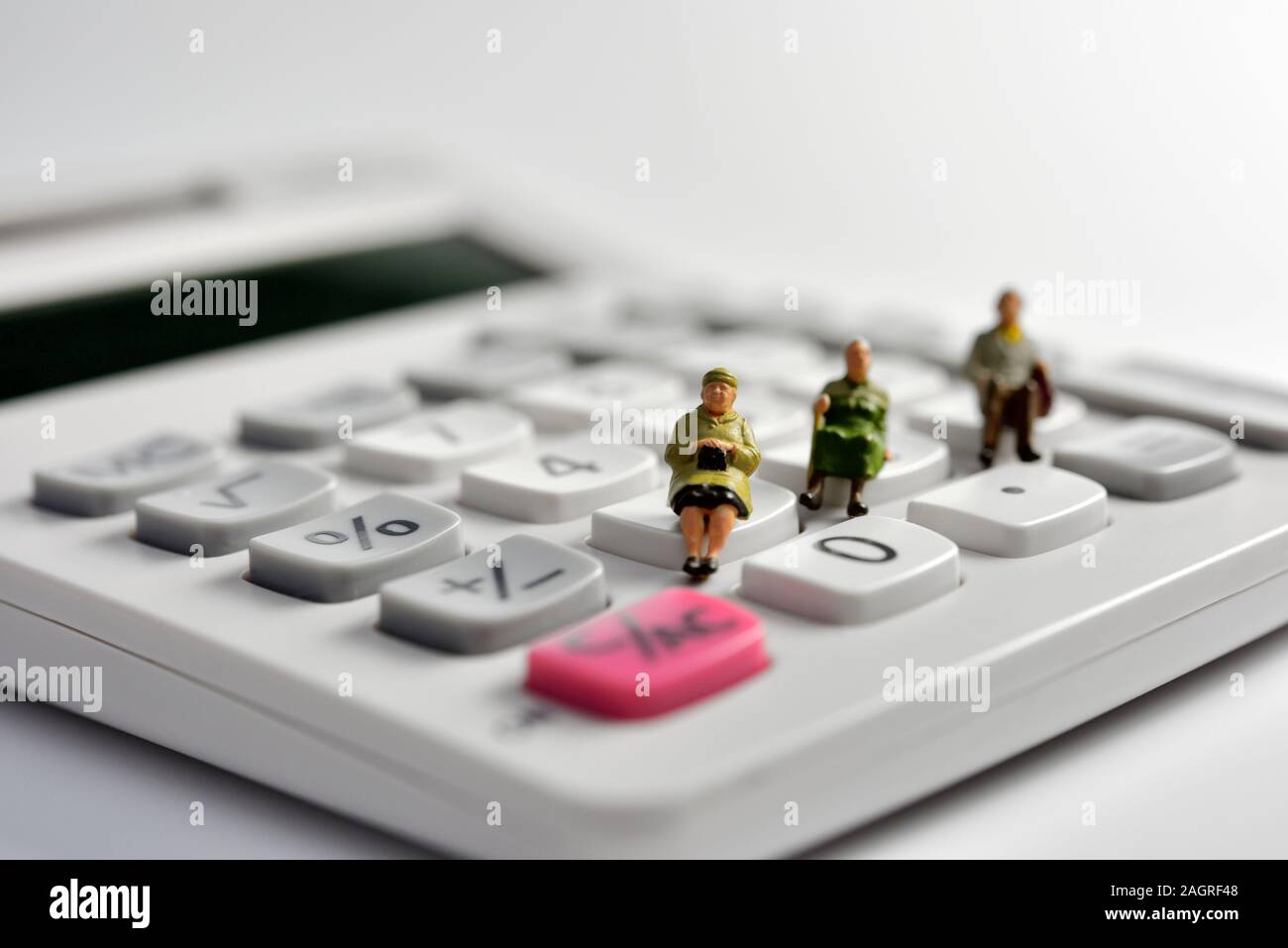 Les retraités miniature assis sur une calculatrice Banque D'Images