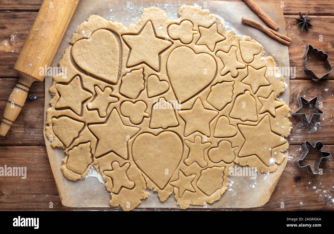 La pâte à biscuits au gingembre avec des figures découpées sur un fond de bois. Vue de dessus Banque D'Images