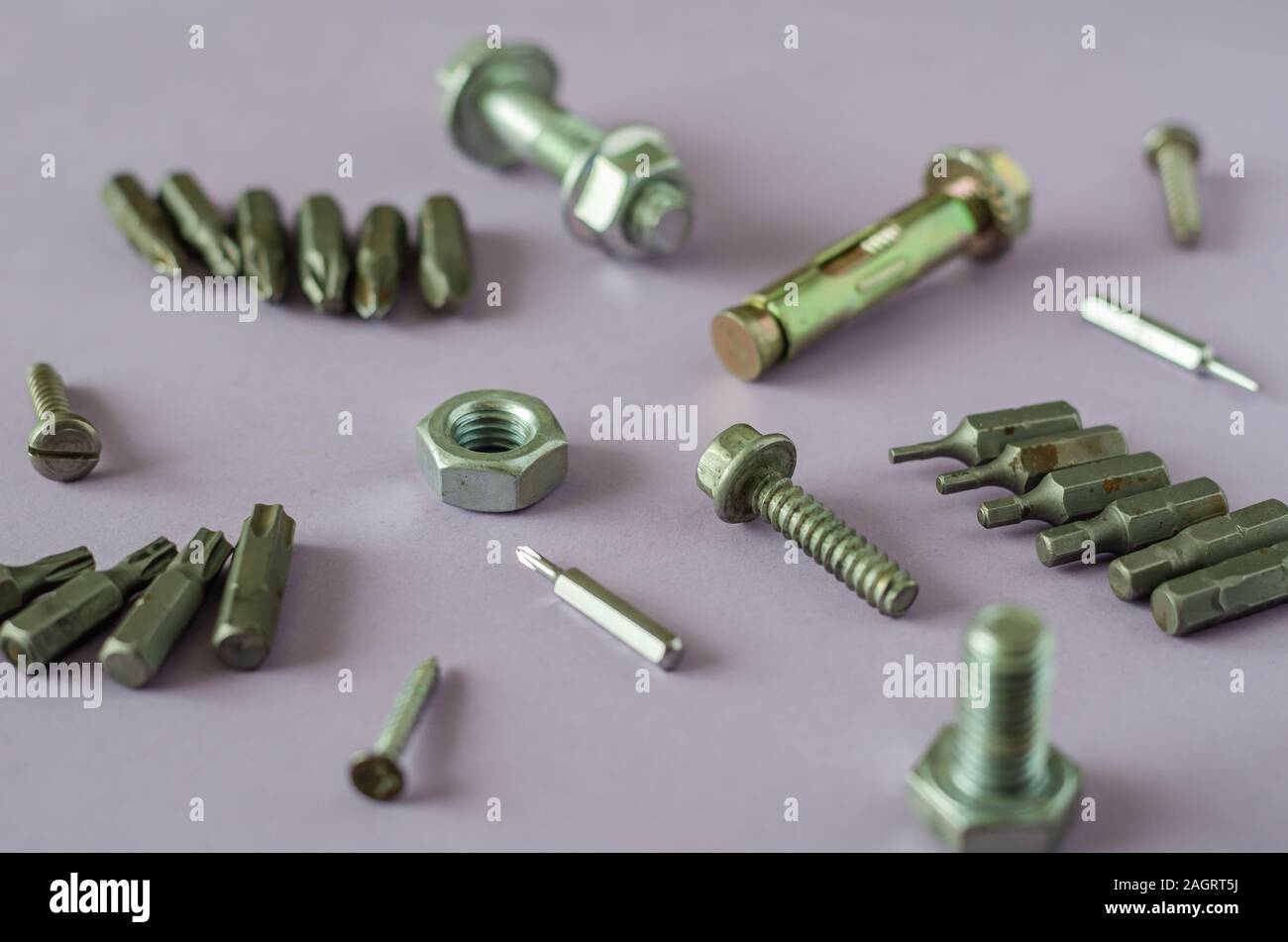 L'objet industriel contexte pour résoudre de nombreux problèmes. Écrou, boulon, vis, embouts pour tournevis plat. Fond clair. Vue de côté. Focus sélectif. Banque D'Images