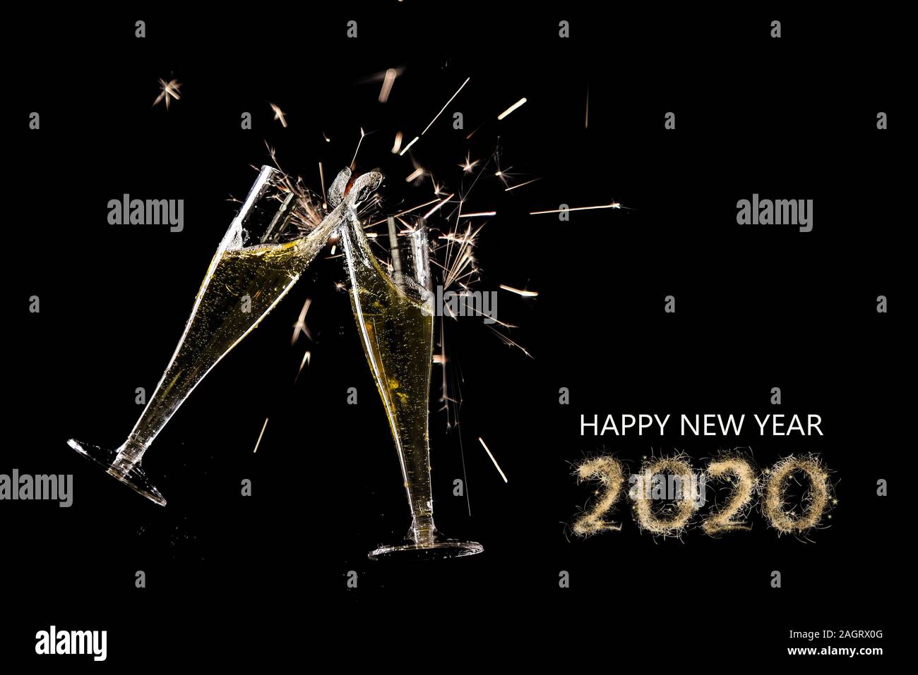 Bonne année 2020, deux flûtes à champagne toast avec splash et cierges sur un fond noir, concept parti avec texte et copy space Banque D'Images