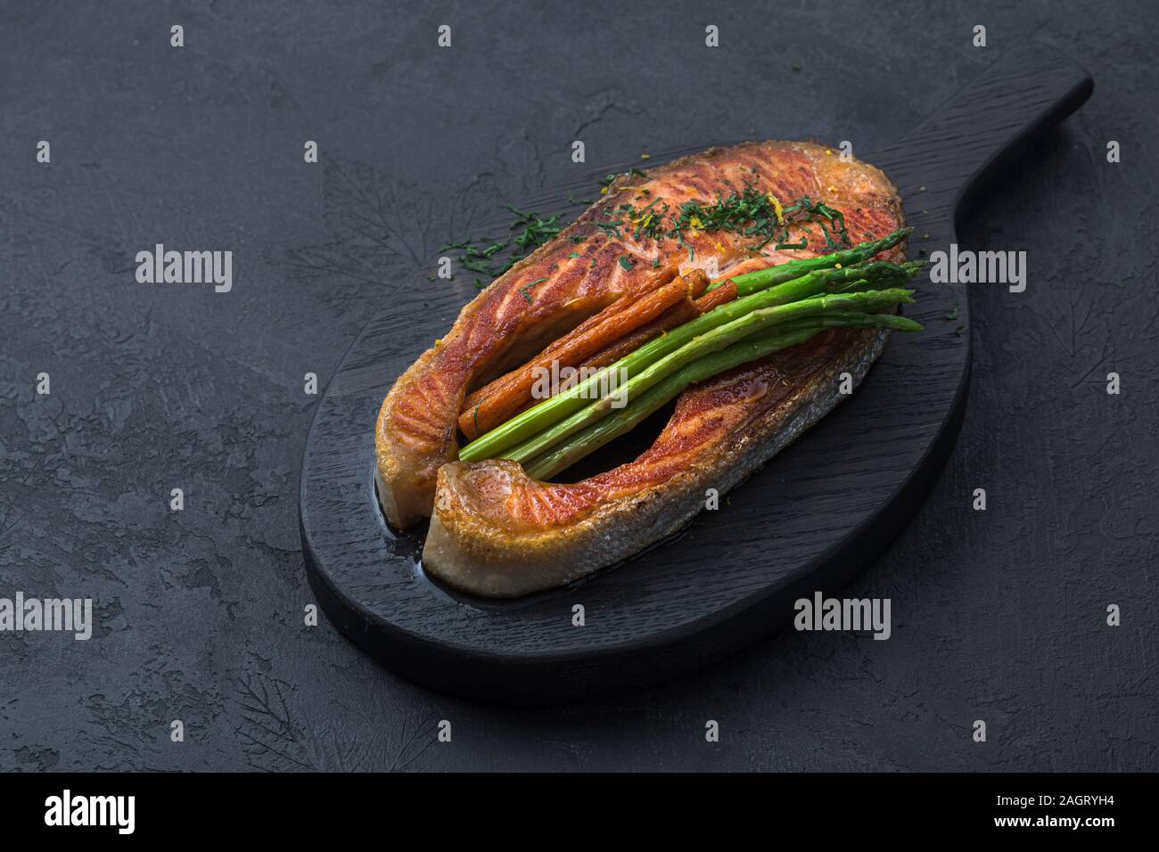 Pavé de saumon poêlé sur planche en bois foncé, noir photo copy space Banque D'Images