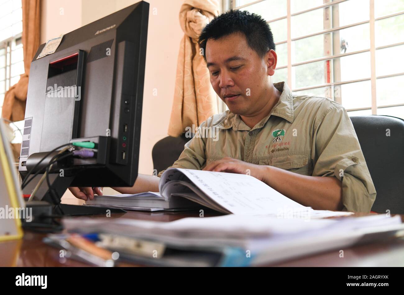 (191221) -- HAIKOU, 21 décembre 2019 (Xinhua) -- Erhui Feng, un ingénieur forestier en Dongzhaigang National Nature Reserve, matériaux chèques à son bureau à la réserve dans le sud de la Chine, province de Hainan, le 18 décembre 2019. Hainan, riche en ressources de la mangrove, compte aujourd'hui environ 5 727 hectares de forêts de mangroves, dont la plupart sont distribués dans une variété de zones protégées - réserves naturelles et parcs nationaux des zones humides. Zhengping Chen, Feng Luo, Erhui Lixiang et Lyu Shiyang sont tous des mangroves de la base de la protection et de la gestion du personnel dans les différentes réserves de mangroves dans la province de Hainan, des responsabilités dans le Banque D'Images