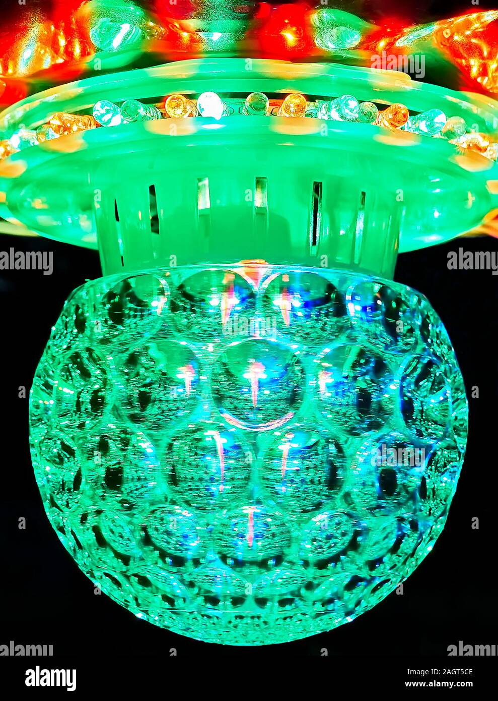 Ampoule ronde en plastique vert, entouré de nombreux feux LED colorés, sur un fond noir Banque D'Images