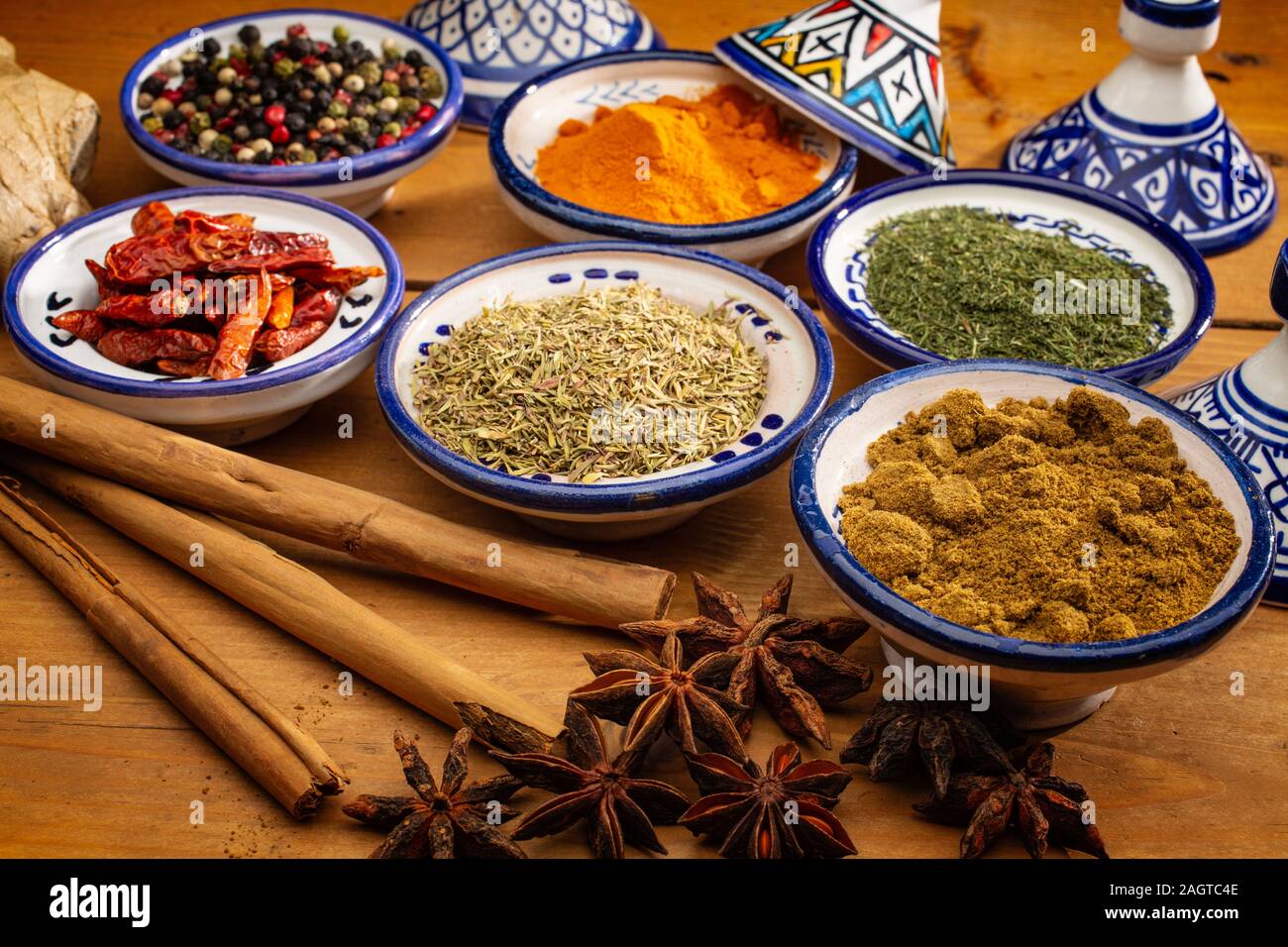 Alimentation saine. Les épices dans des contenants en céramique typique du Maroc sur une vieille table en bois. Poivre de couleur, le curcuma, le piment de cayenne, la cannelle, gingembre, cumin, star Banque D'Images