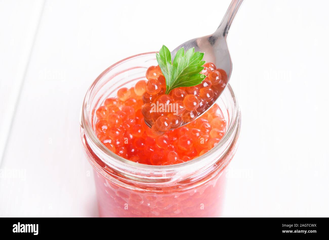 Caviar rouge avec le persil et la cuillère dans un bol en verre blanc sur fond de bois Banque D'Images