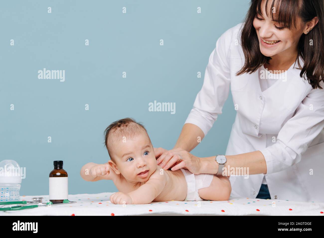 Jeune femme médecin examine un bébé garçon et sourit Banque D'Images