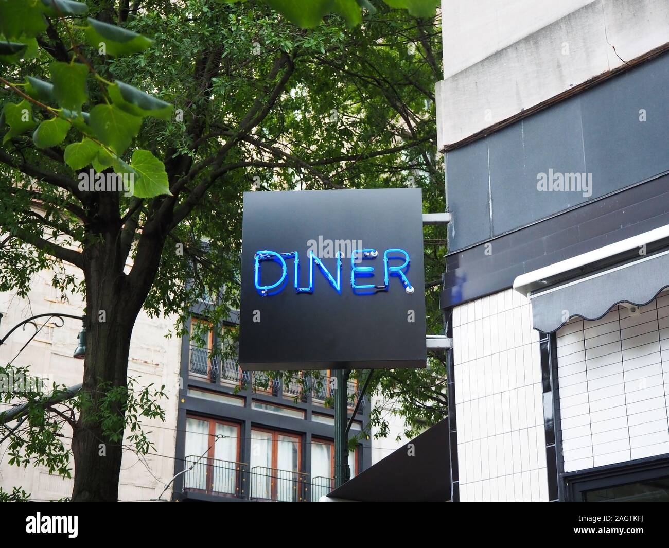 Une enseigne au néon lumineux lit Diner fixé à l'angle d'un ancien bâtiment du centre-ville sur une rue bordée d'arbres. Banque D'Images