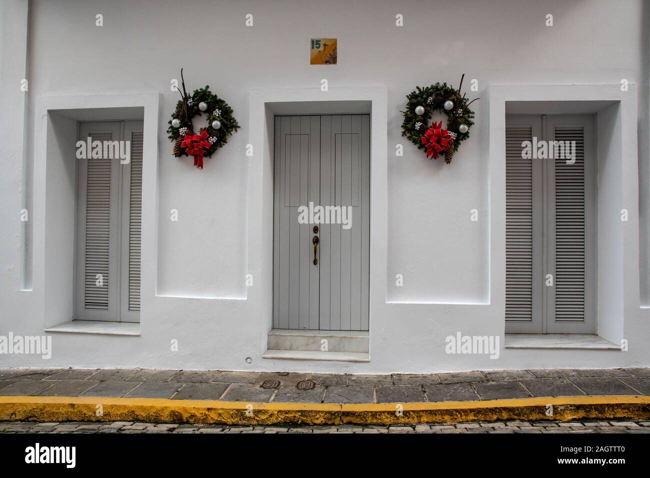 Ces porte et le windows 2 font partie d'un bâtiment maison peint en blanc dans la vieille ville historique de San Juan. Les murs blancs sont ornés de 2 couronnes. Banque D'Images