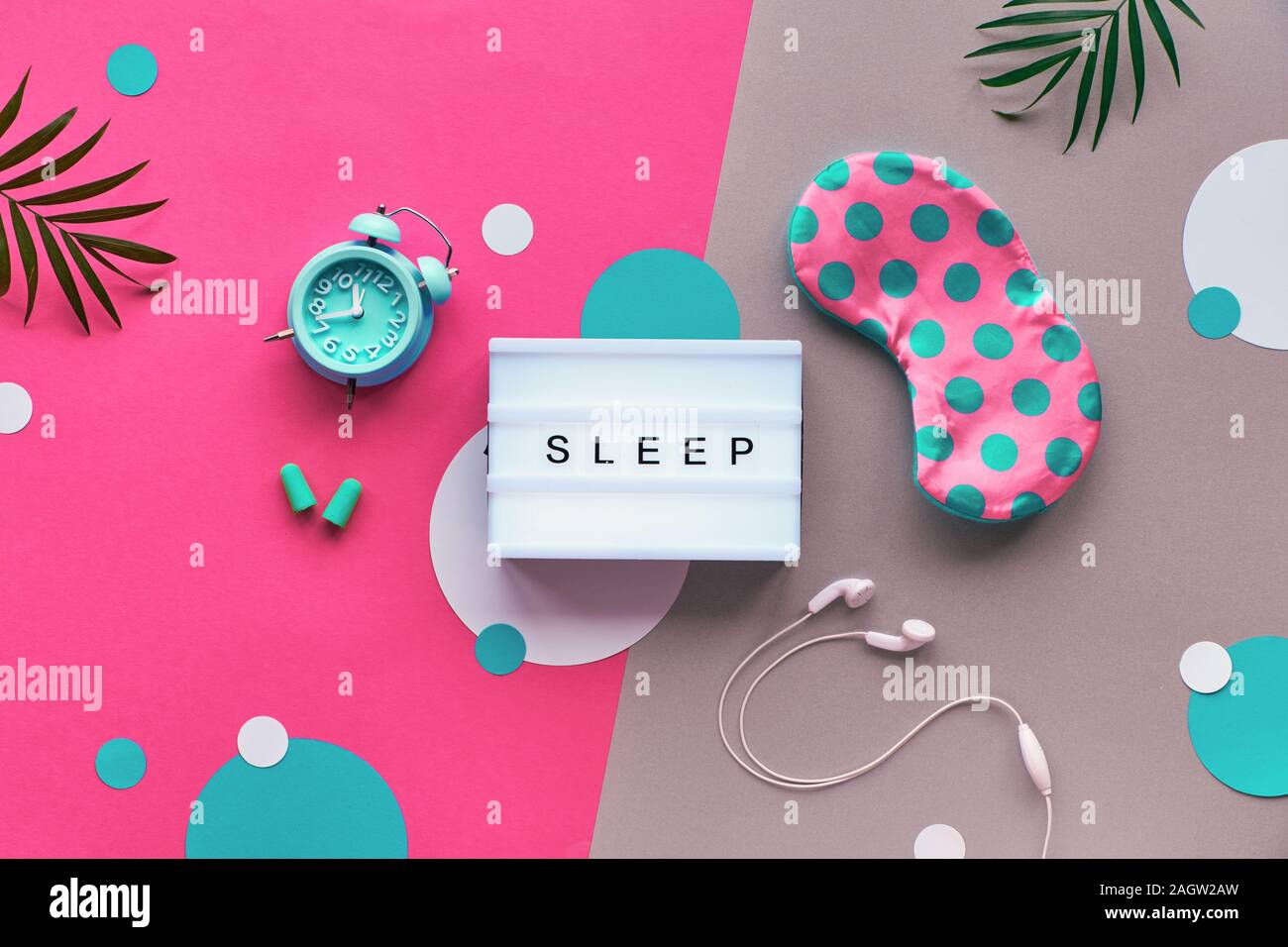 Nuit de sommeil sain concept créatif. Masque de sommeil, menthe bleue, alarme, bouchons d'écouteurs. Deux tons rose et fond argenté avec des cercles de papier et Banque D'Images