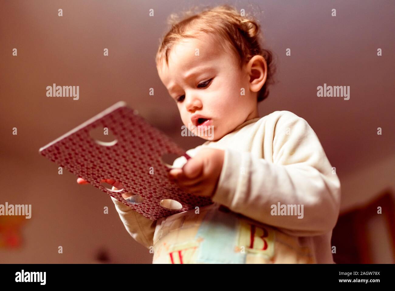 Bébé jouant avec un carton comprimé à la maison. Banque D'Images