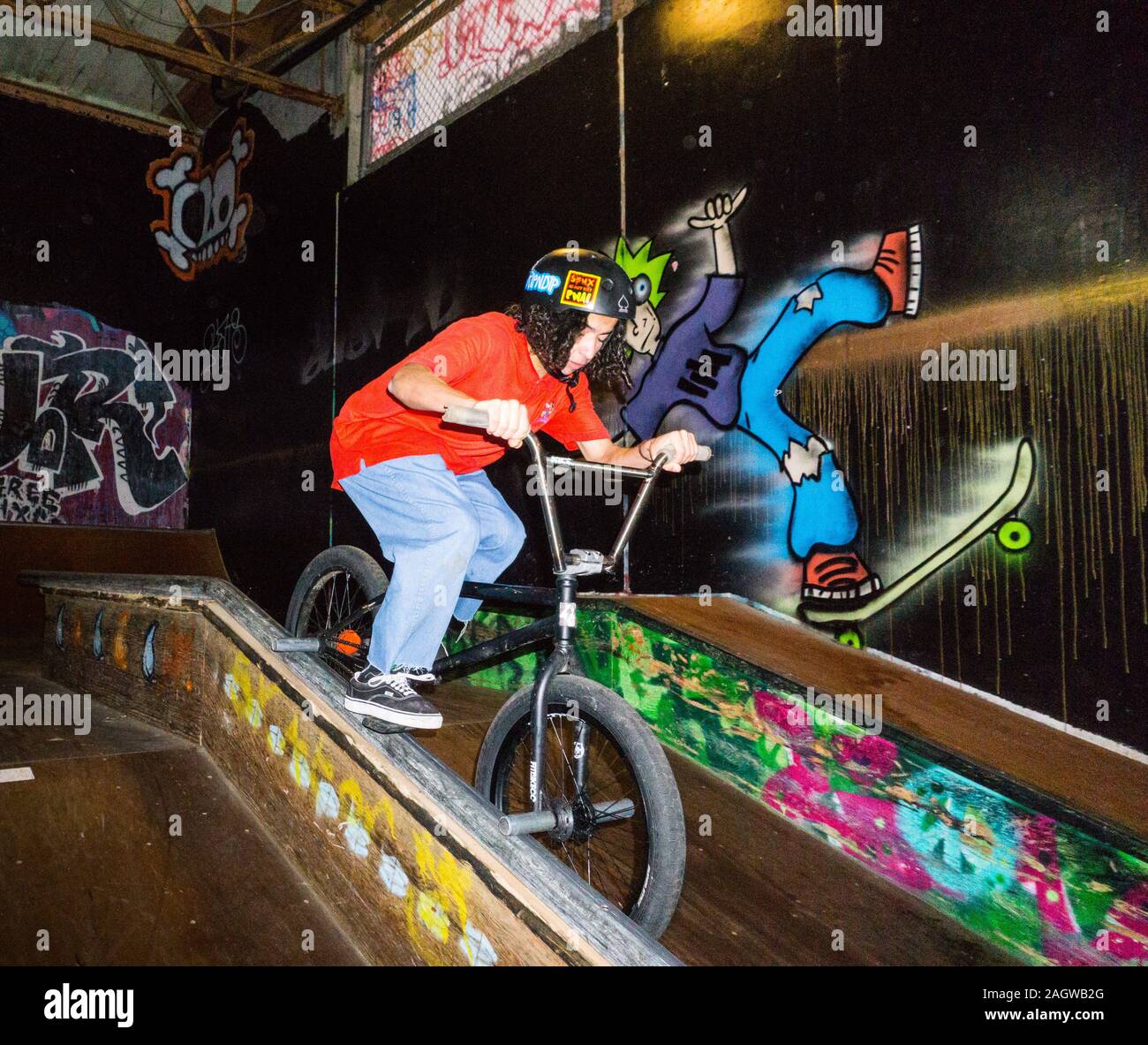 Un athlète extrême BMX urbain circonscription à une piscine skate park avec beaucoup de graffitis. Banque D'Images