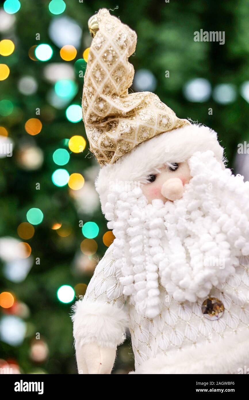 Funny Santa gnome jouet avec barbe blanche sur fond flou de couleurs des lumières d'arbre de Noël. Banque D'Images