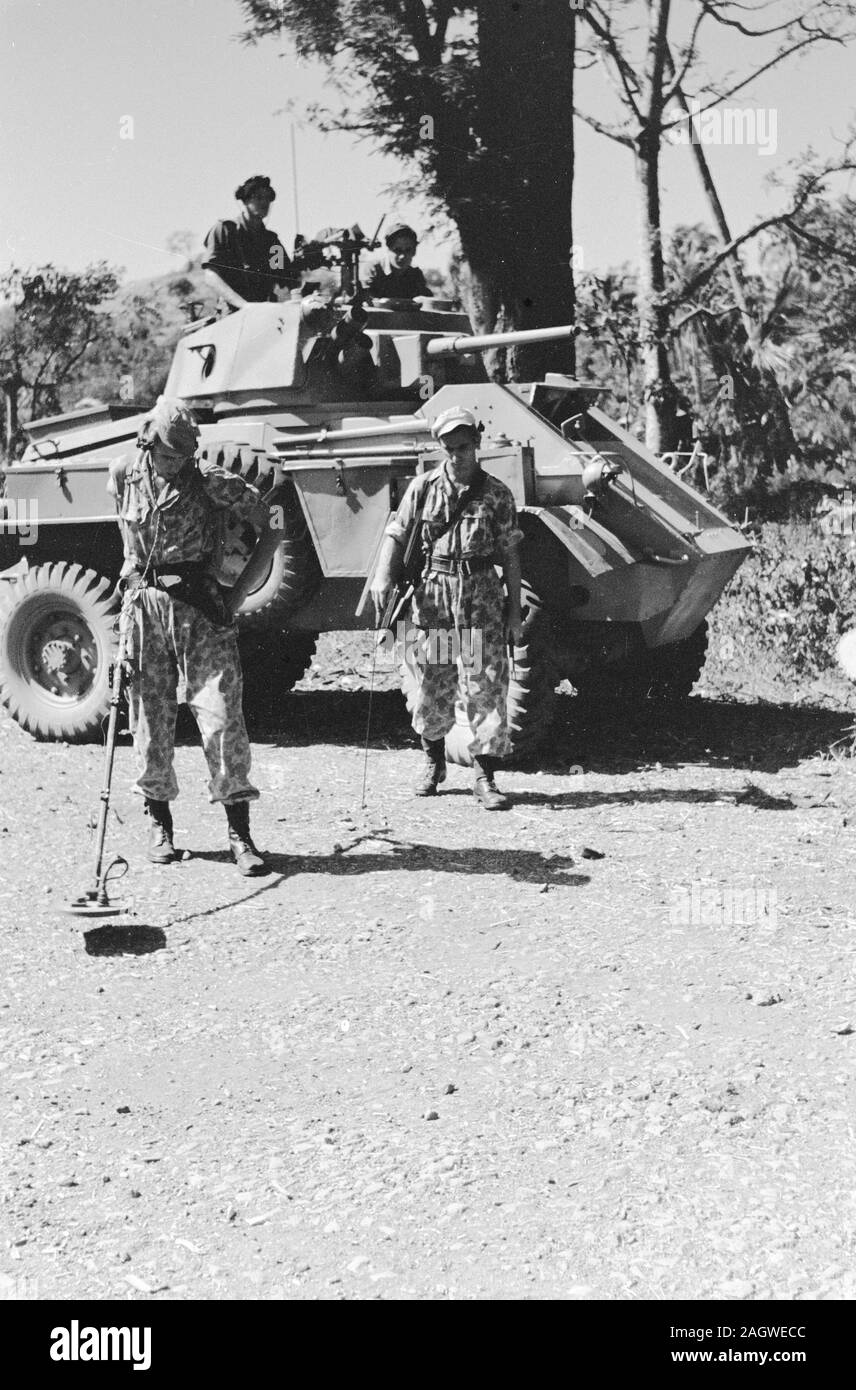 Soldat avec un détecteur de métal à la recherche de mines. Derrière lui une voiture blindée Humber ; Date Juin 1947 ; Lieu de l'Indonésie, Indes néerlandaises Banque D'Images