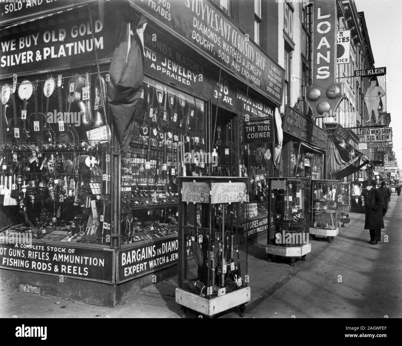 Stuyvesant curiosity shop, avec des fusils, des jumelles, dans les cas à l'avant ; les instruments, couteaux, d'autres marchandises en fenêtre, Prêt et 'fat men's' shop. Magasin de jouet, 48, Troisième Avenue, Manhattan. ca. 1937 Banque D'Images
