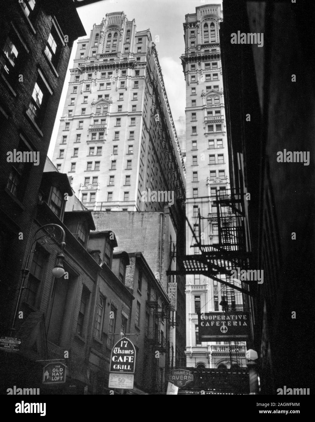 Avis de Thames Street, Manhattan New York Scène de rue. Faible, les vieux bâtiments, les panneaux pour Bars, cafétéria, etc. coopérative, lampadaires et firsecapes en premier plan, les immeubles de grande hauteur dans la lumière au-delà de ca. 1938 Banque D'Images