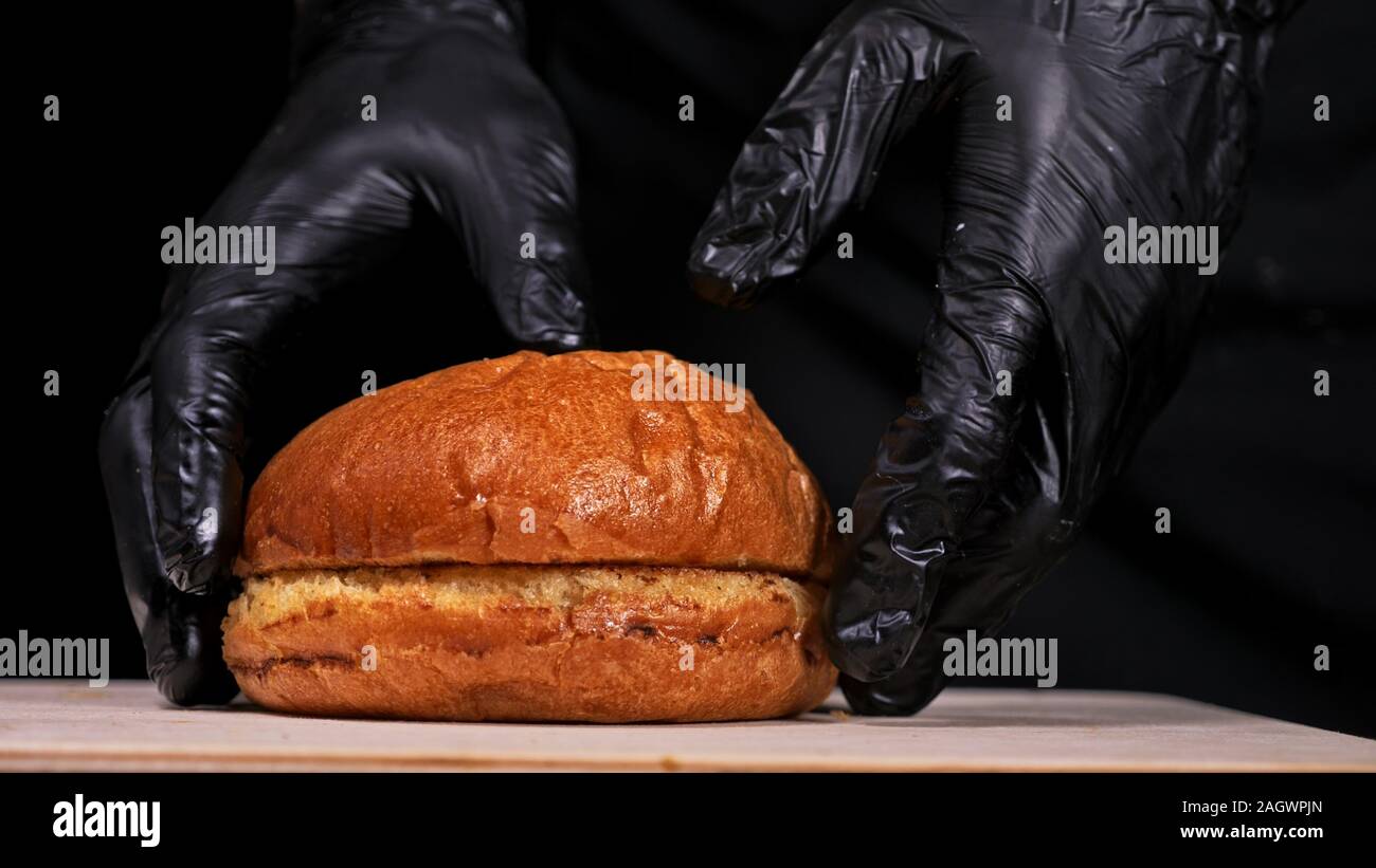Burger d'artisanat est cuisson sur fond noir. Composé : sauce, roquette, tomate, oignon, bacon, fromage ricotta, sauce au cassis, pain d'air et en viande. Banque D'Images Burger d'artisanat est cuisson sur fond noir. Composé : sauce, roquette, tomate, oignon, bacon, fromage ricotta, sauce au cassis, pain d'air et en viande. Banque D'Images