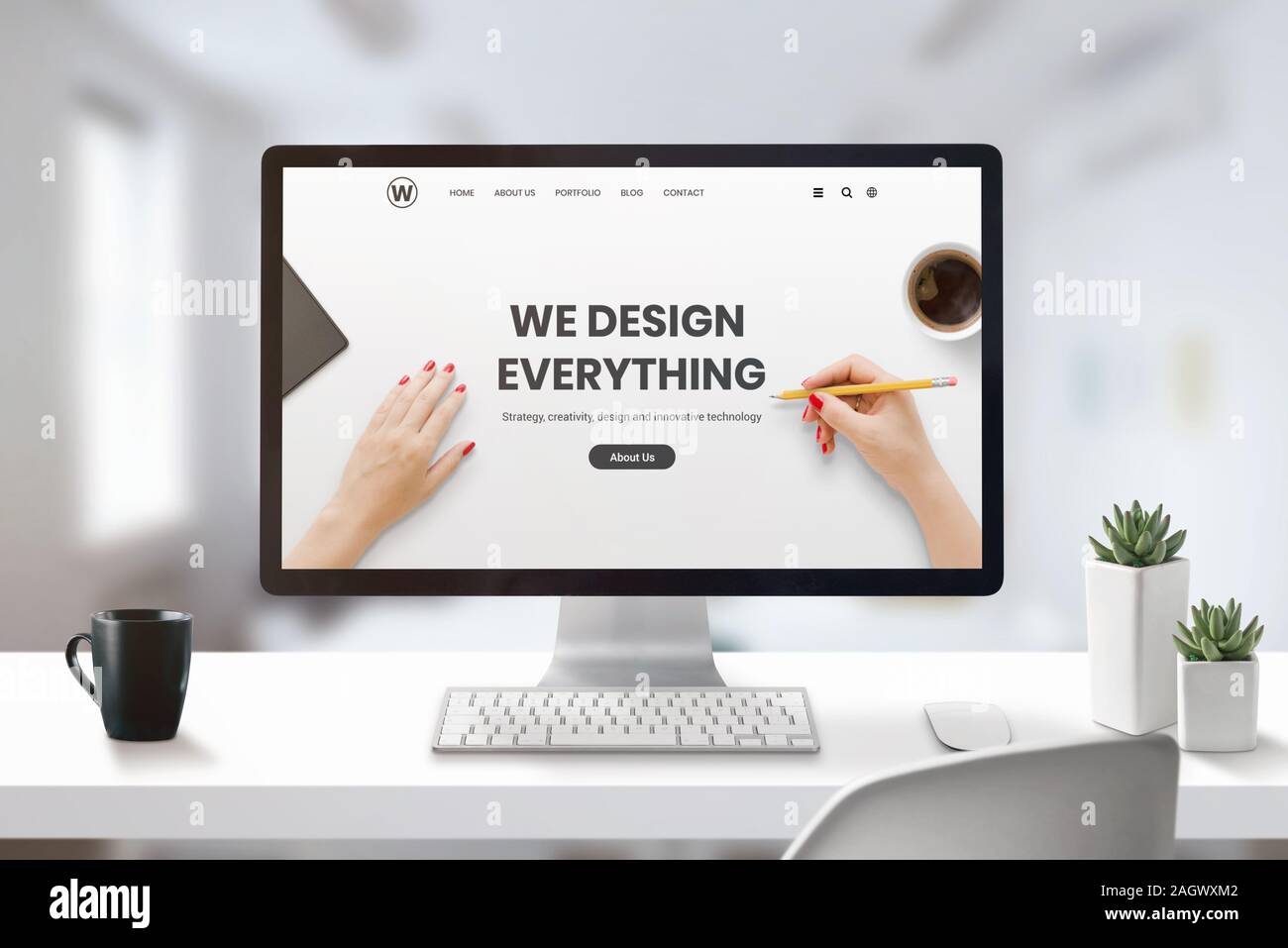 Web design studio concept avec l'agence moderne page web sur l'écran de l'ordinateur. Bureau, Studio 24 avec tasse de café et les plantes à côté Banque D'Images