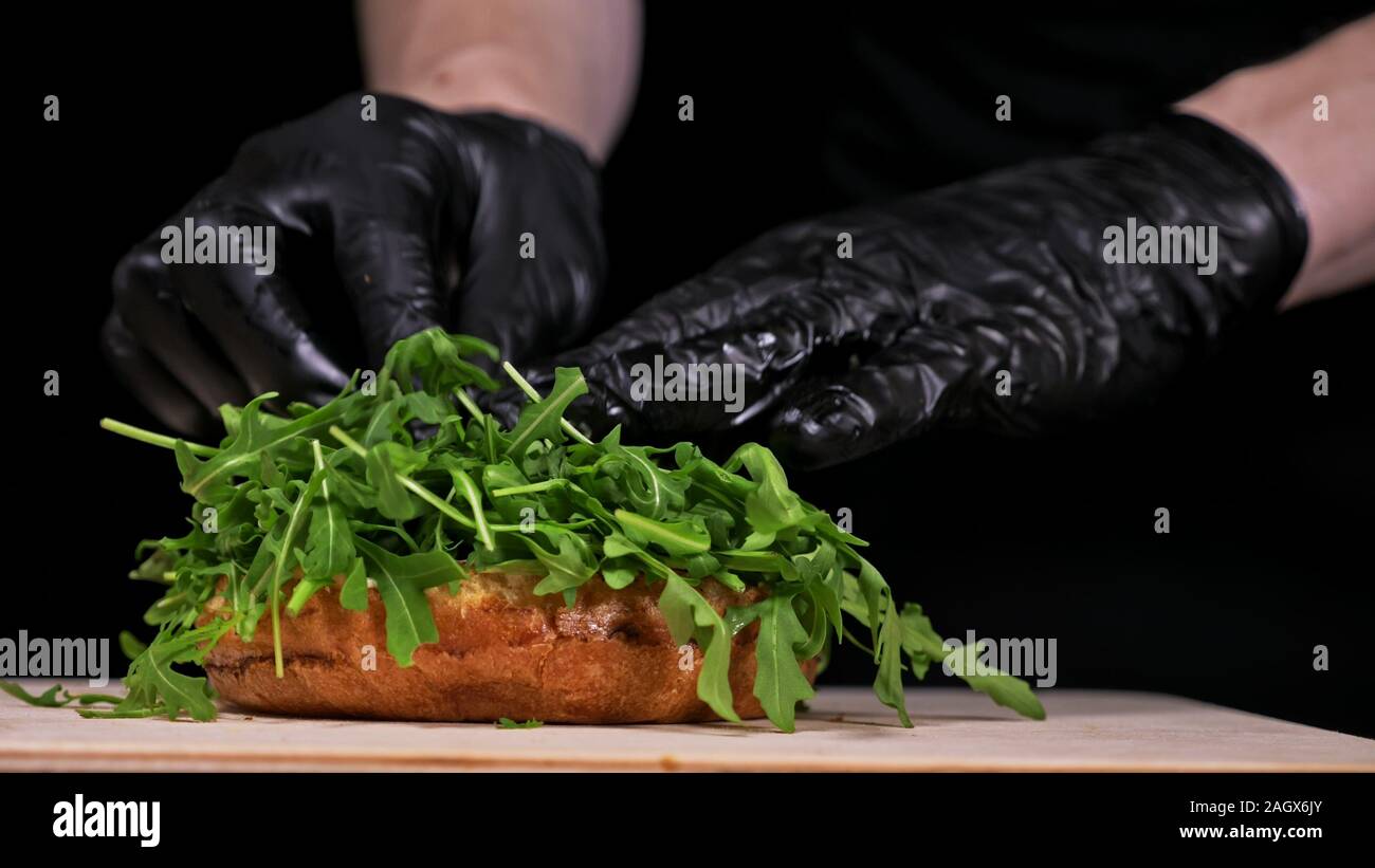 Burger d'artisanat est cuisson sur fond noir. Composé : sauce, roquette, tomate, oignon, bacon, fromage ricotta, sauce au cassis, pain d'air et en viande. Banque D'Images Burger d'artisanat est cuisson sur fond noir. Composé : sauce, roquette, tomate, oignon, bacon, fromage ricotta, sauce au cassis, pain d'air et en viande. Banque D'Images