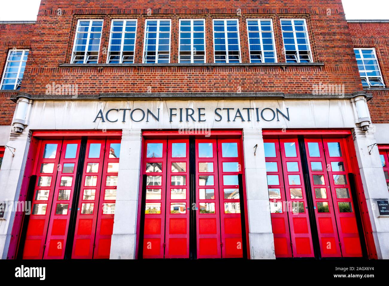 Une partie de l'entrée avant d'Acton Fire Station, avec des portes peintes en rouge. Gunnersbury Lane. Acton, West London, W3, Angleterre, Royaume-Uni. Banque D'Images