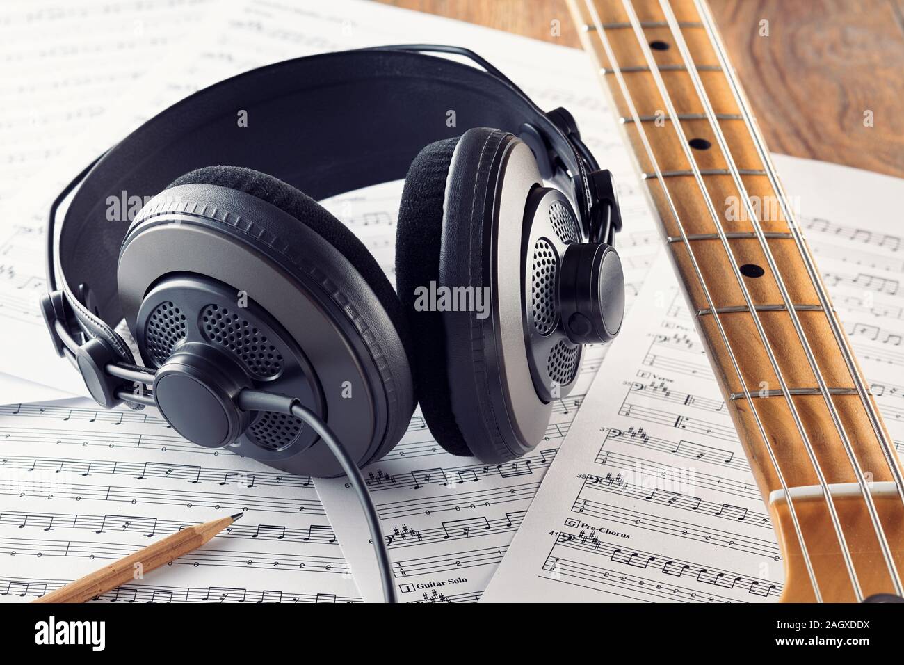 Casque de studio professionnel et guitare basse cou sur feuilles de musique de fond. Concept d'enregistrement de musique ou la composition. Vue en gros plan. Banque D'Images