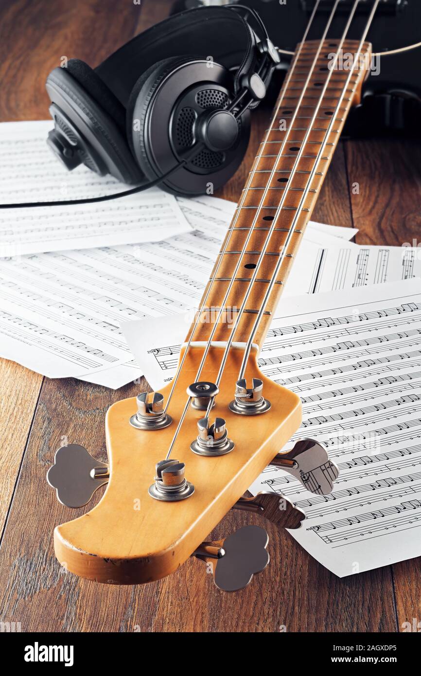 Guitare basse du cou, casque de studio et des partitions sur table en bois.  Concept de l'enregistrement de la musique, jouer ou composer. Vue en gros  plan Photo Stock - Alamy