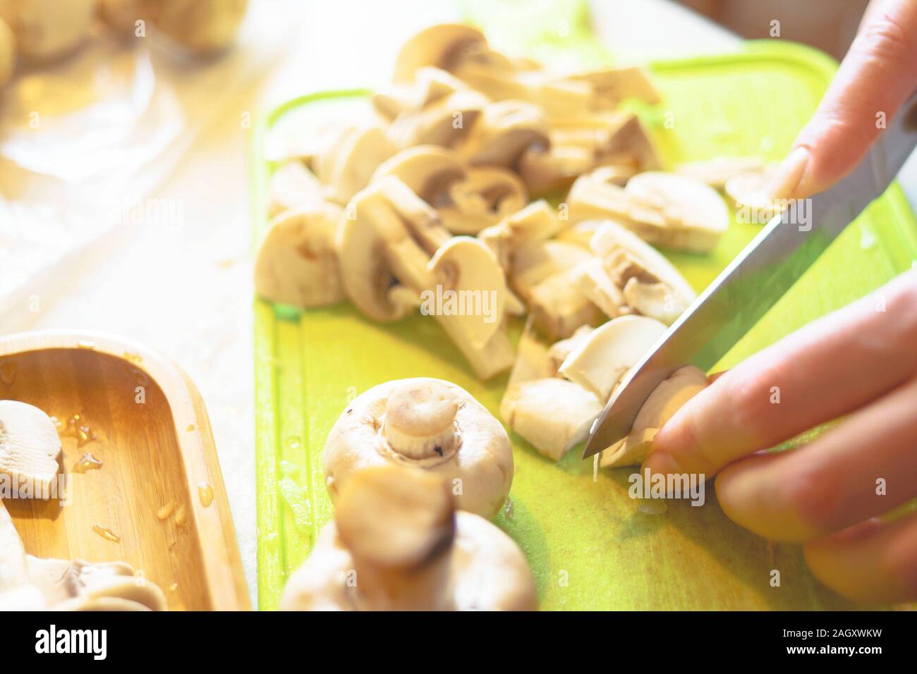Femme coupe champignons. Champignons hachés sur un bac en plastique vert Banque D'Images