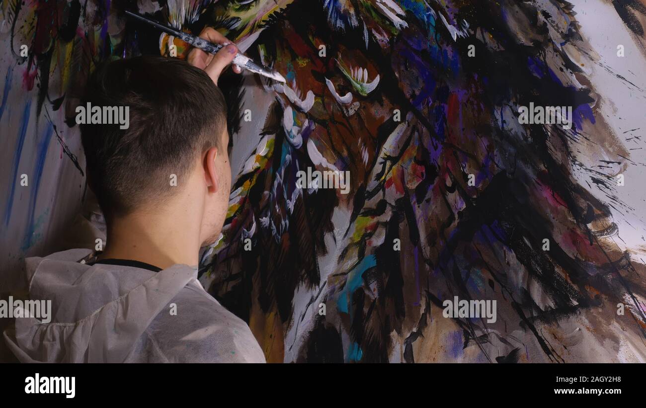 Concepteur de l'artiste dessine un aigle sur le mur. Décorateur artisan photo peintures à l'acrylique couleur d'huile. Peintre peintre vêtu de couche de peinture. À l'intérieur. Banque D'Images