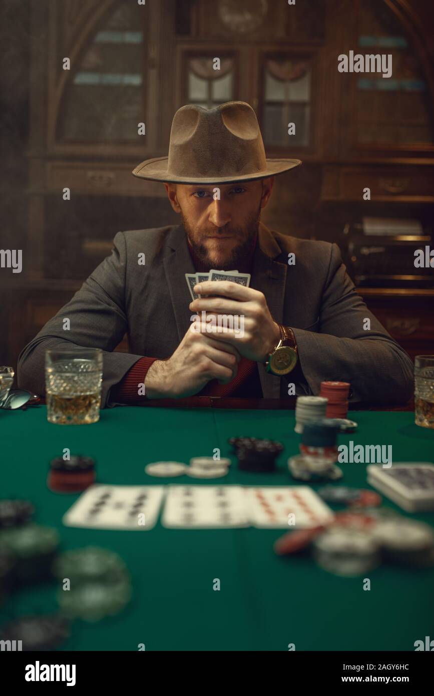 Joueur de poker en costume et chapeau joue dans le casino, risque de  dépendance. Jeux de hasard. Homme loisirs dans la maison de jeu, table de  jeu avec tissu vert Photo Stock -