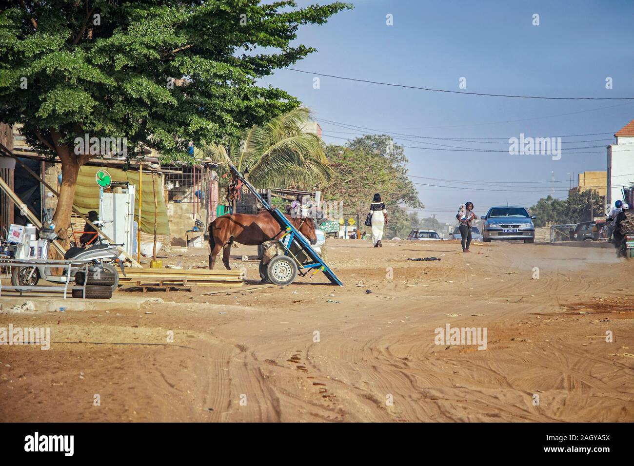 Mbour, Sénégal - Apr 26, 2019 : femme sénégalaise non identifiés avec bébé dans une route poussiéreuse au milieu de la ville. Il y a une voiture sur la Banque D'Images