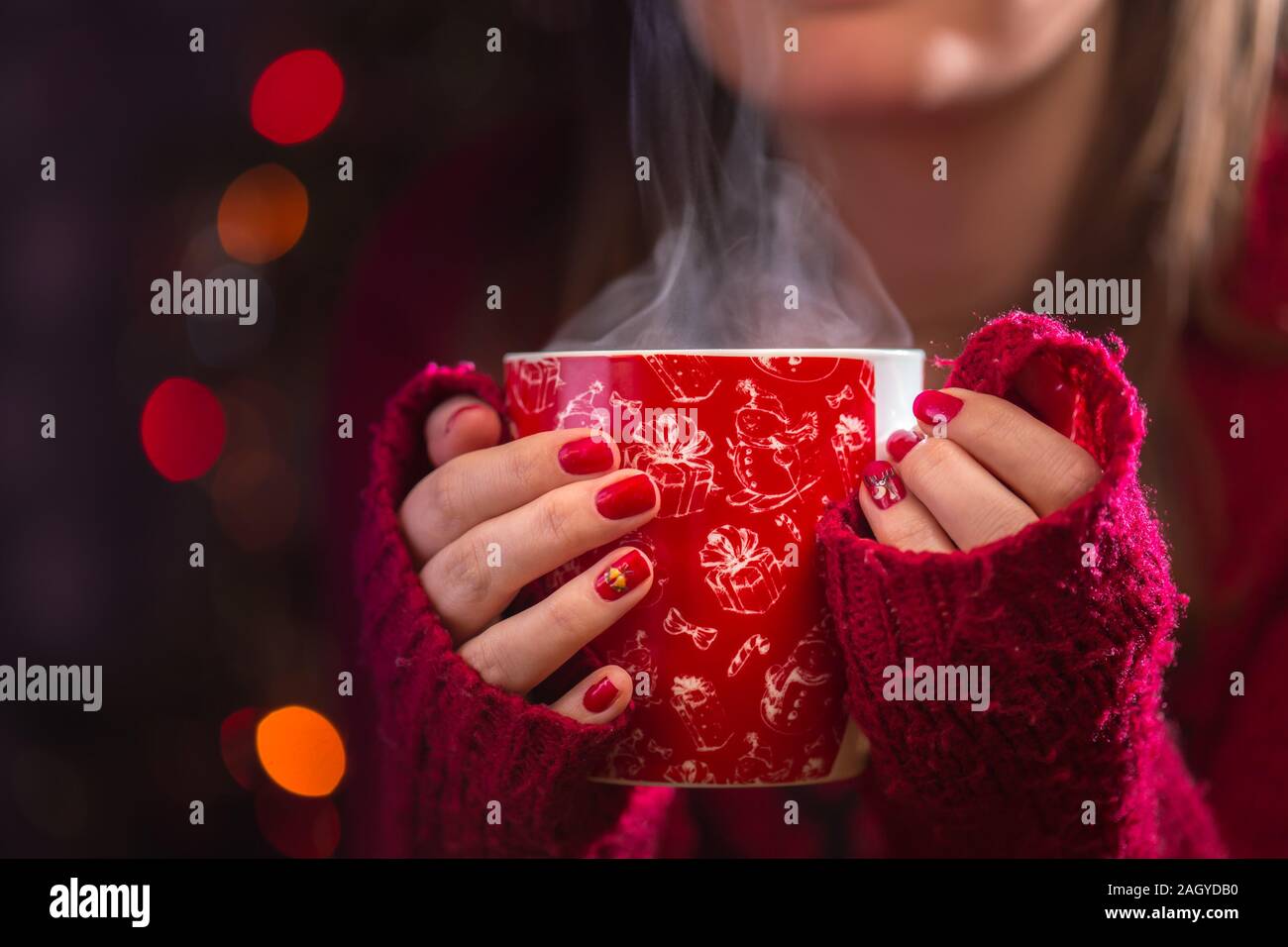 Détail de femme mains tenant une tasse de thé chaud à la vapeur. Noël arrière-plan flou. Concept d'hiver ou de noël. Banque D'Images