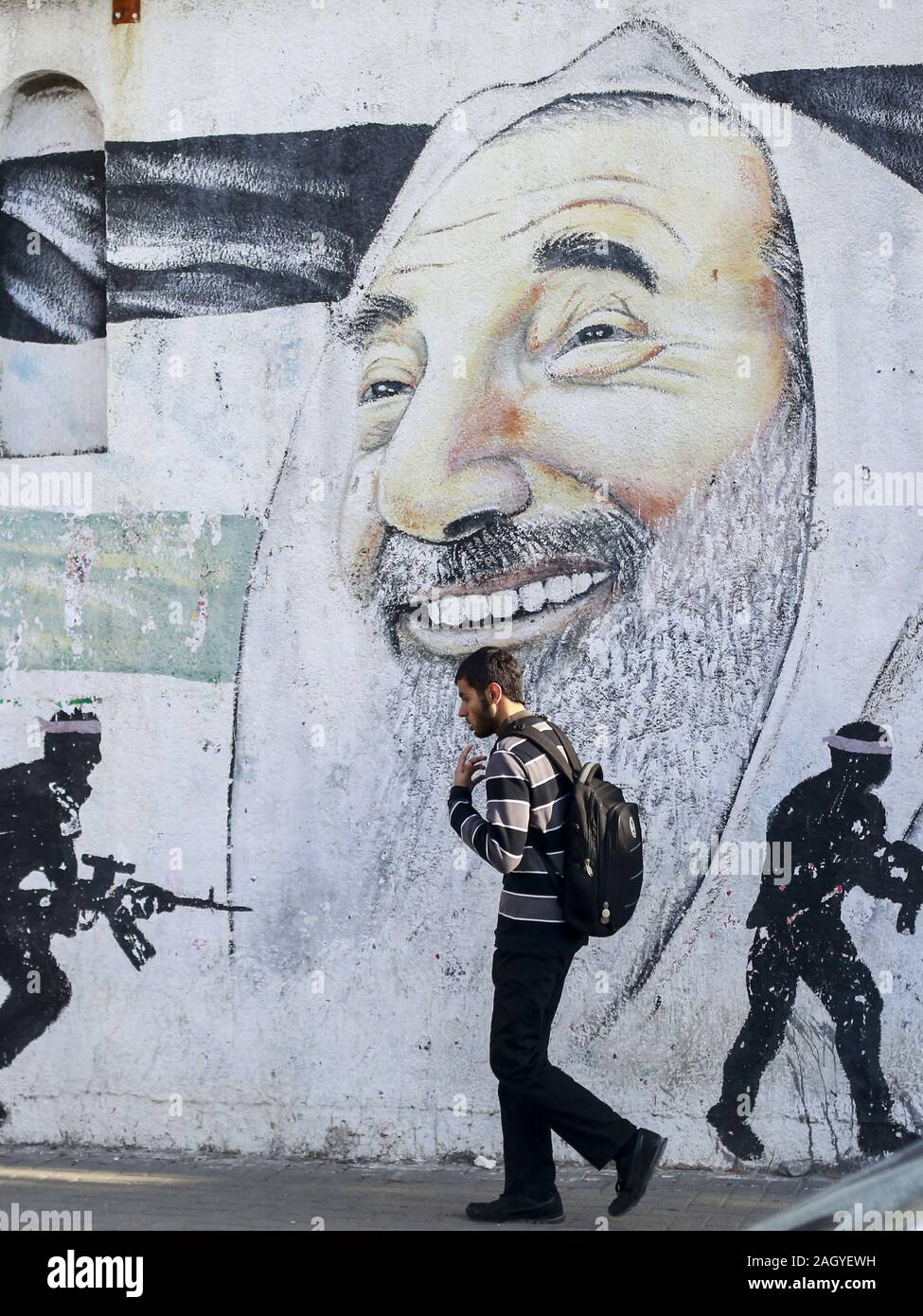 La ville de Gaza, en Palestine. Dec 22, 2019. Un Palestinien passe devant une peinture murale représentant le chef spirituel du Hamas, cheikh Ahmed Yassine, et des combattants masqués de la Brigades Al-Qassam, la branche armée du Hamas, à Gaza. Credit : Mahmoud Issa/SOPA Images/ZUMA/Alamy Fil Live News Banque D'Images