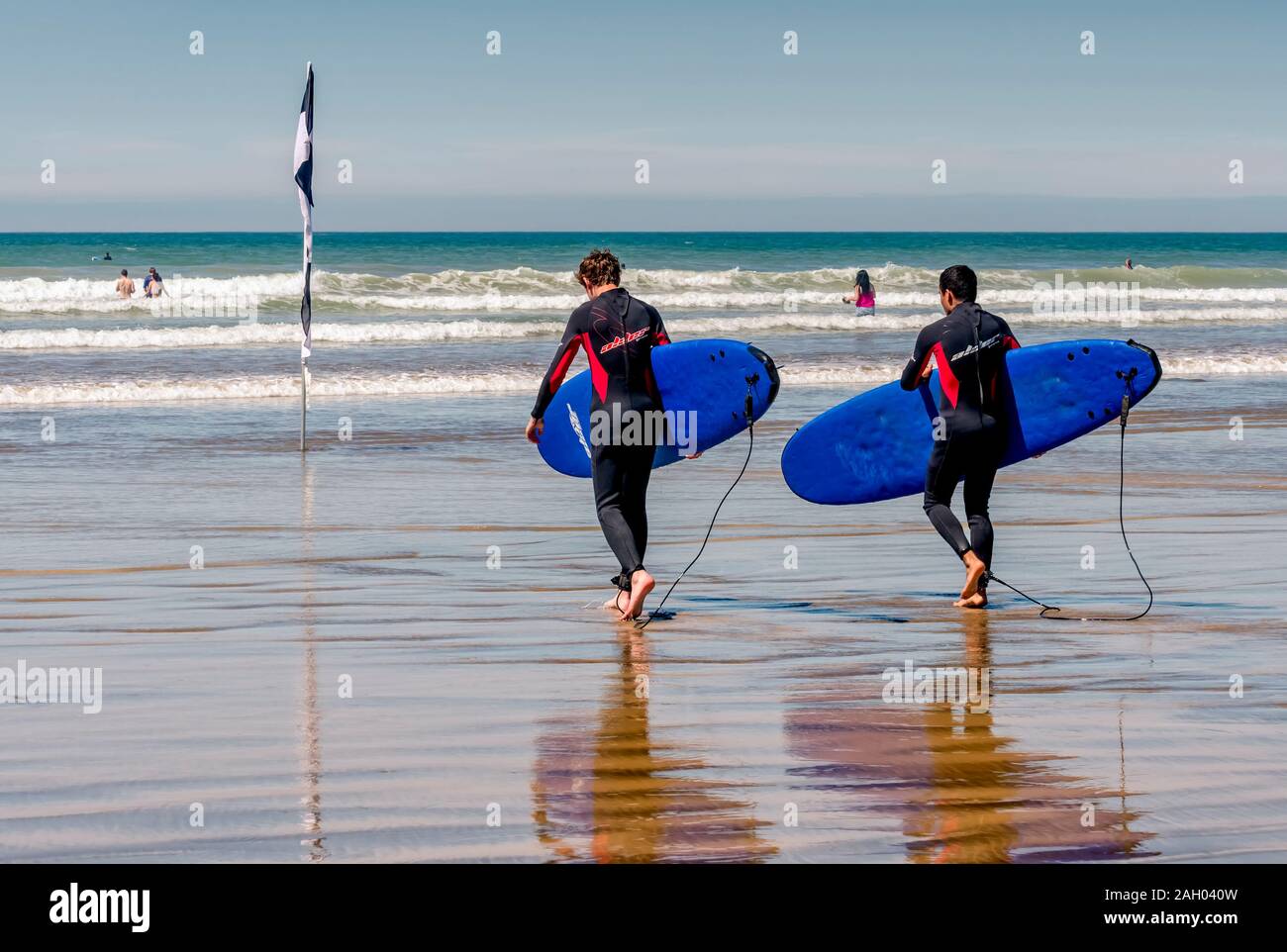 Deux surfeurs avec planches de surf bleues, sur Westward Ho! Plage, North Devon, Royaume-Uni Banque D'Images