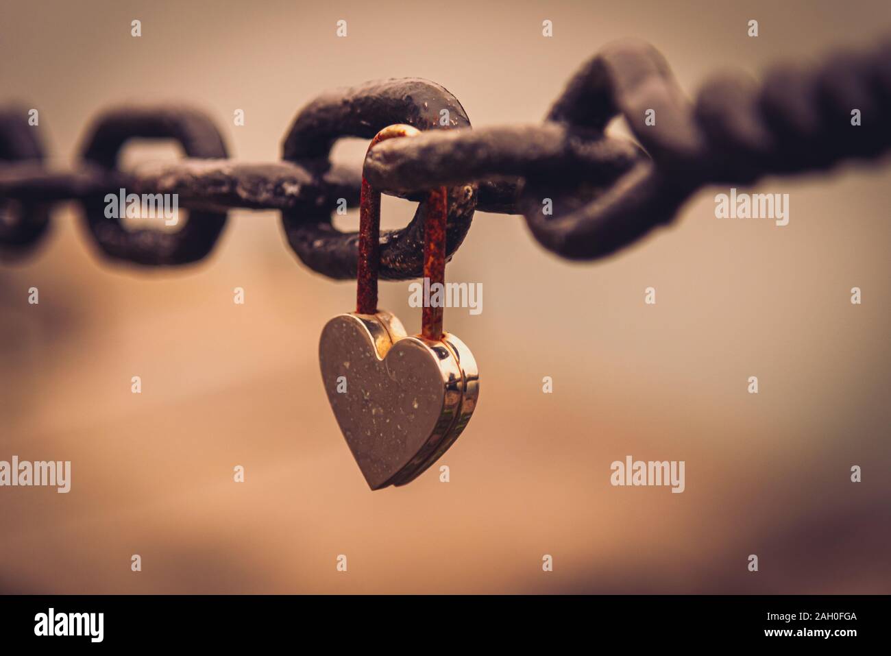 Un romantique et fermée en forme de coeur rouillé suspendu à un cadenas à côté d'une chaîne avec la rivière paysage flou en arrière-plan. Concept de longue durée Banque D'Images