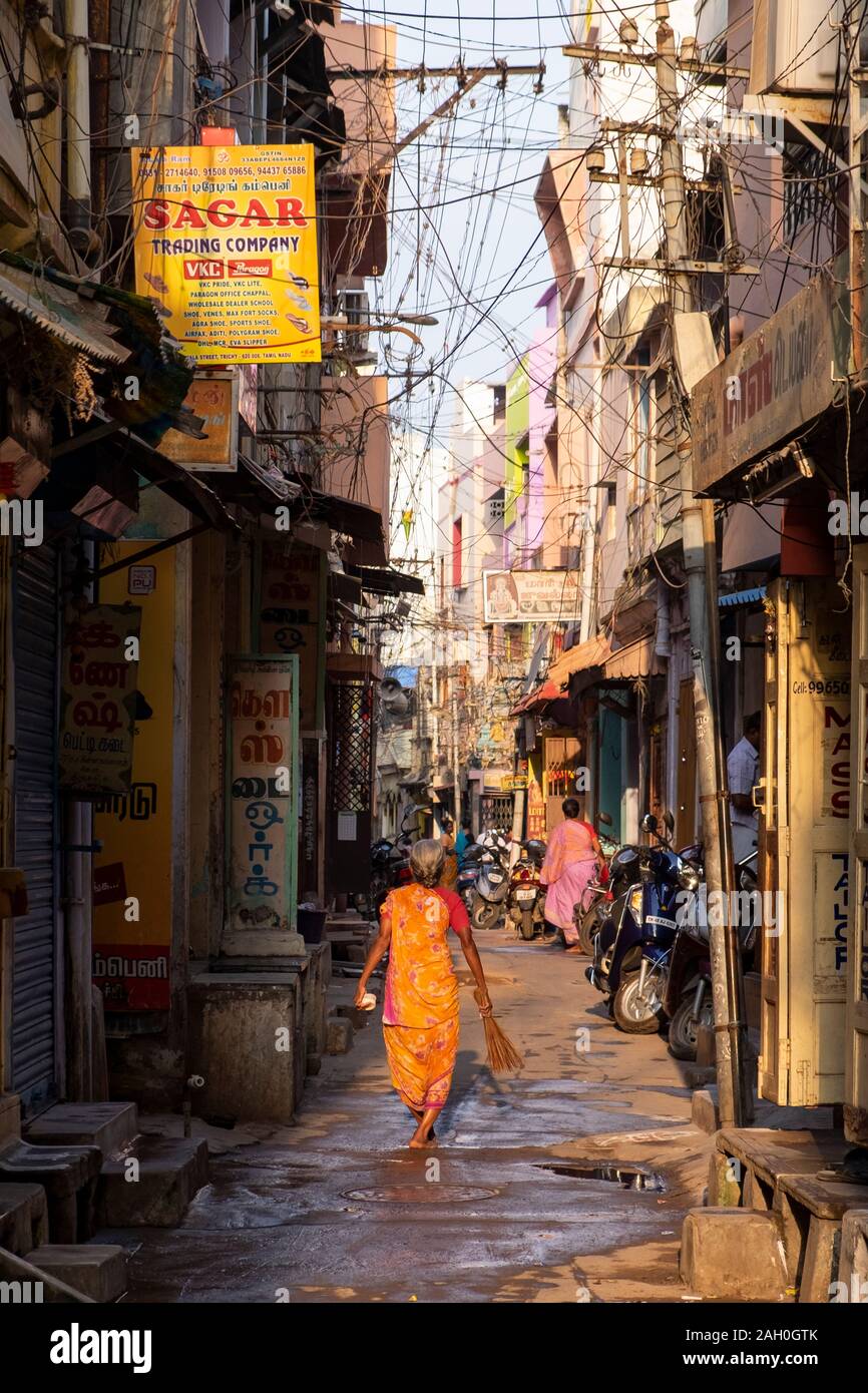 Vue arrière des hauts femme en sari holding broom en marchant dans la ruelle, Trichy, Tamil Nadu, Inde Banque D'Images