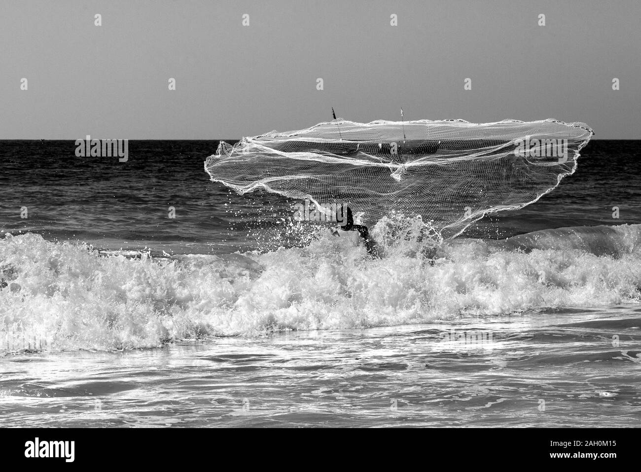 Un pêcheur local, jetant son filet dans les eaux chaudes de la baie du Bengale. La plage de Ngapali, à l'État de Rakhine, au Myanmar Banque D'Images