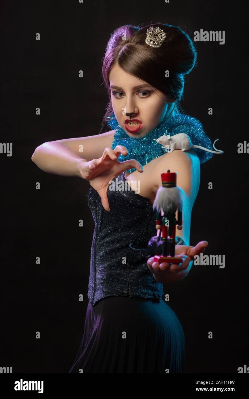Fille en costume reine de la souris joue avec Casse-noisette toy sur fond noir Banque D'Images