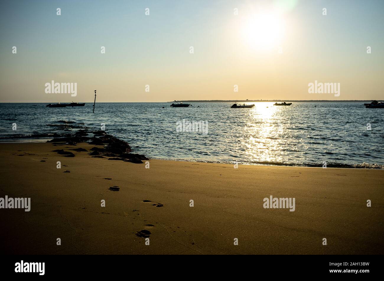 Beau coucher du soleil à plage avec de petites embarcations en arrière-plan Banque D'Images