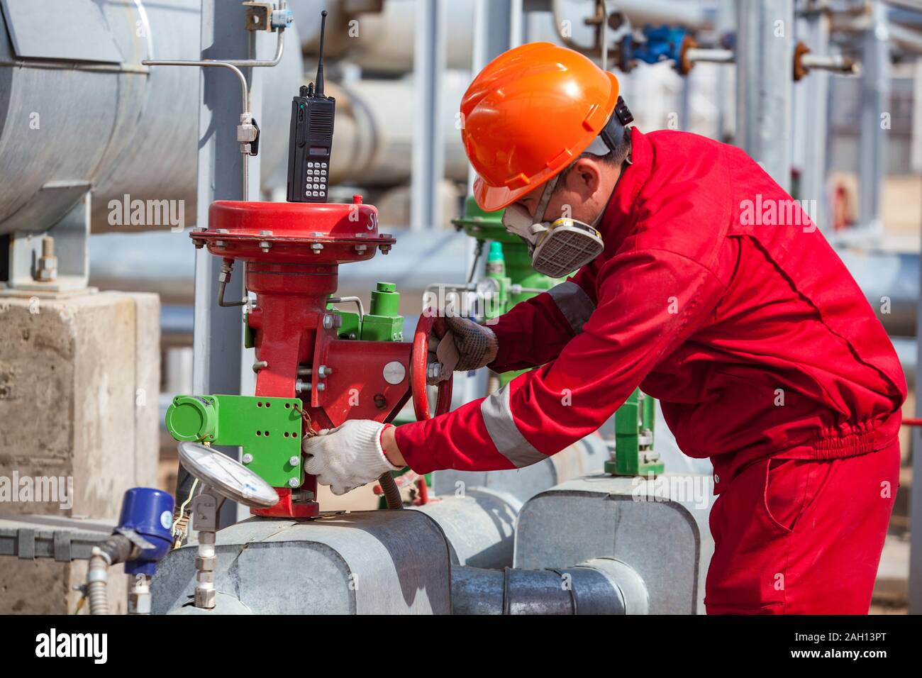 Travailleur en vêtements rouges et orange, casque et masque à gaz oil refinery plant. Banque D'Images