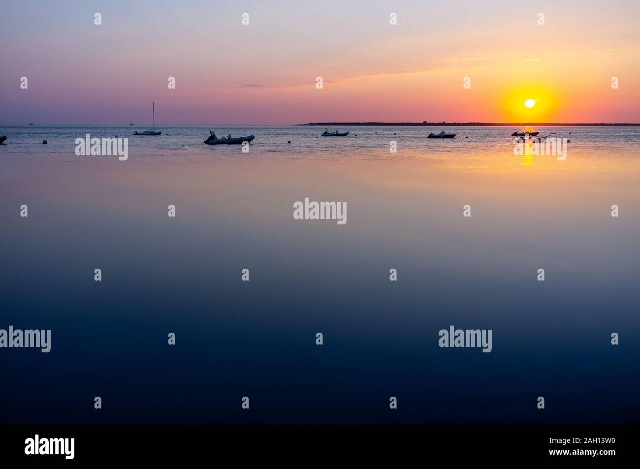 Soleil qui se reflète dans la mer calme avec beaucoup de petits bateaux Banque D'Images