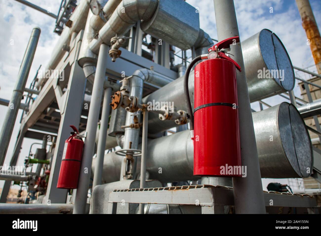 L'usine de raffinerie de pétrole dans le désert. Extincteur rouge. Ciel bleu avec des nuages. Les tuyaux gris et pipe-lines. Banque D'Images