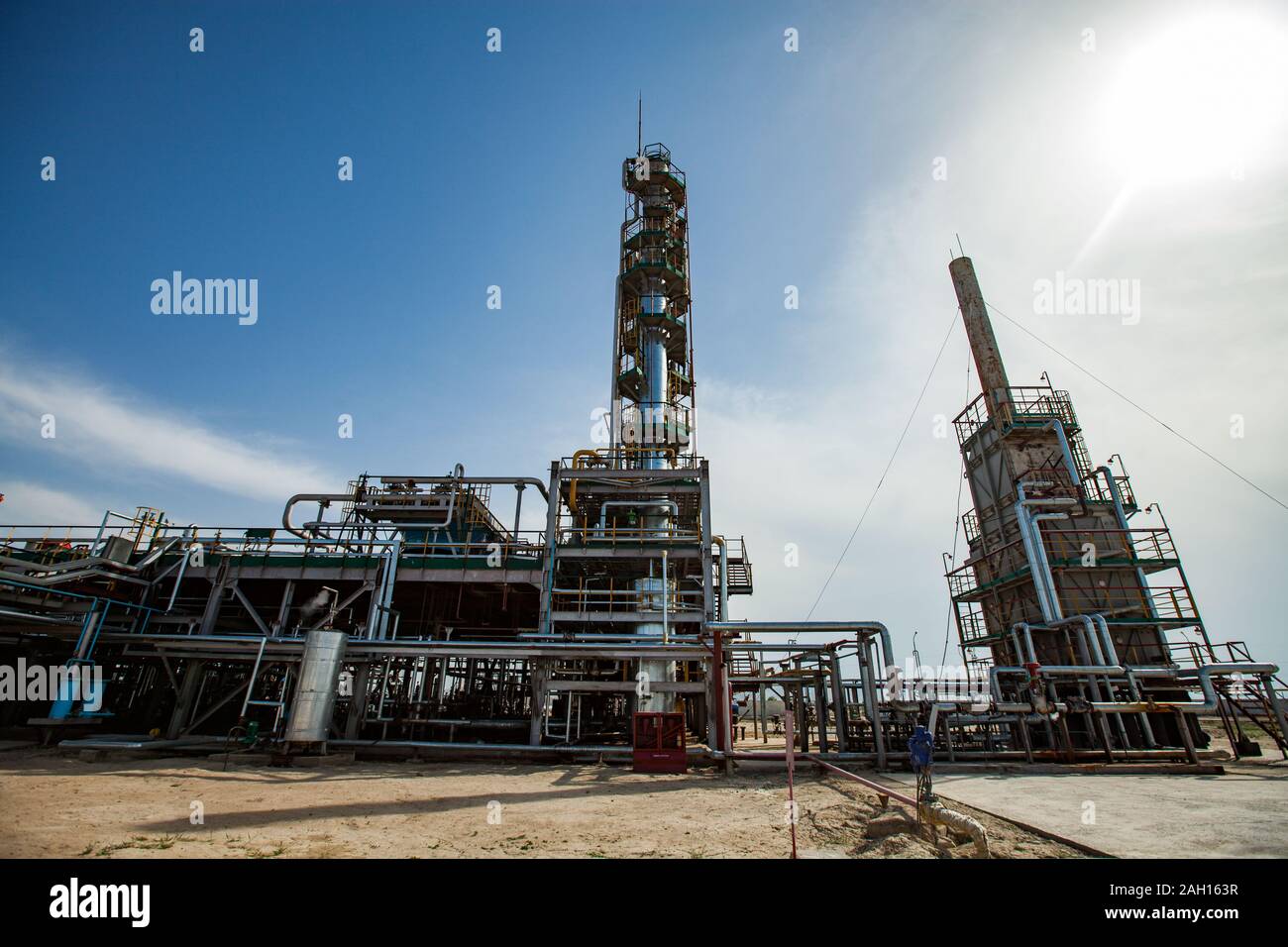 Colonne de distillation gris sur un soleil éclatant dans un ciel bleu avec des nuages. sur l'usine de raffinerie de pétrole dans le désert. Banque D'Images