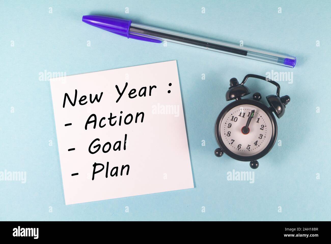 Stylo, papier avec nouvelle année, action, objectif, plan et réveil noir sur fond bleu Banque D'Images