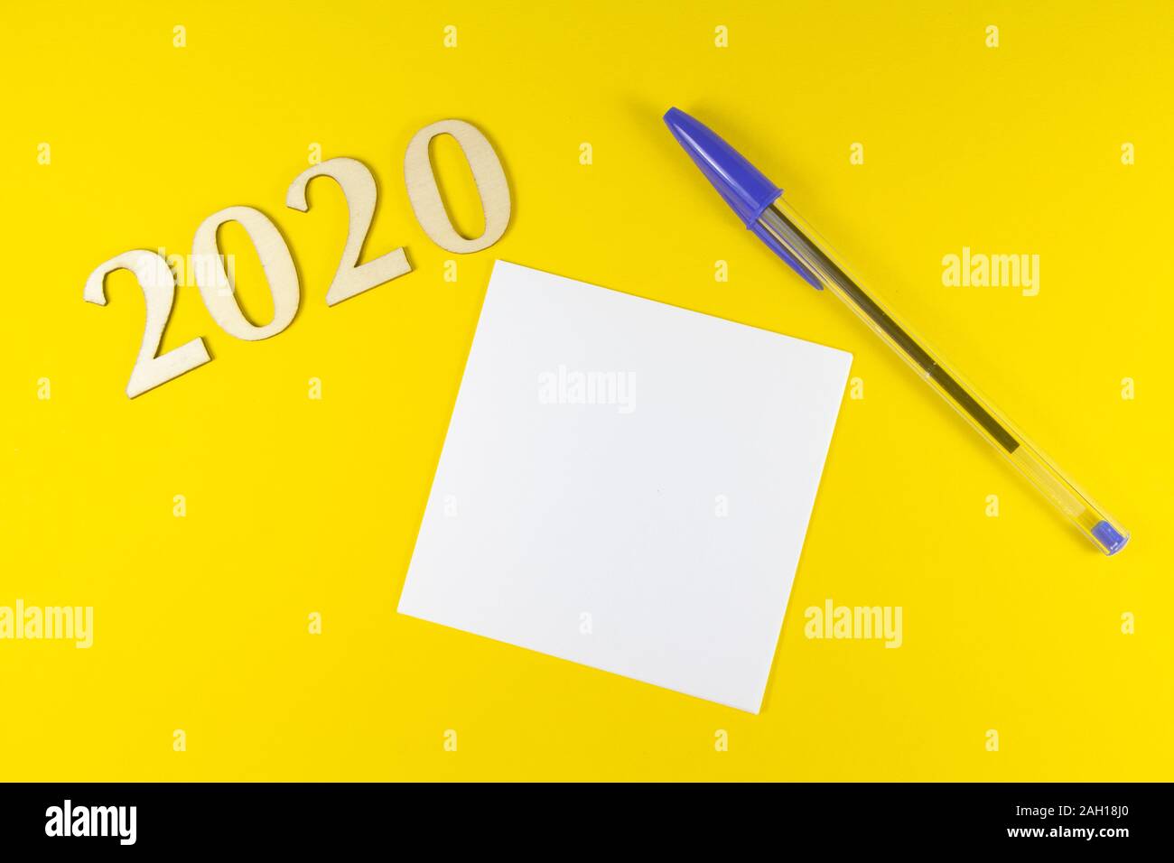 Stylo, papier et en 2020 figures en bois sur fond jaune Banque D'Images