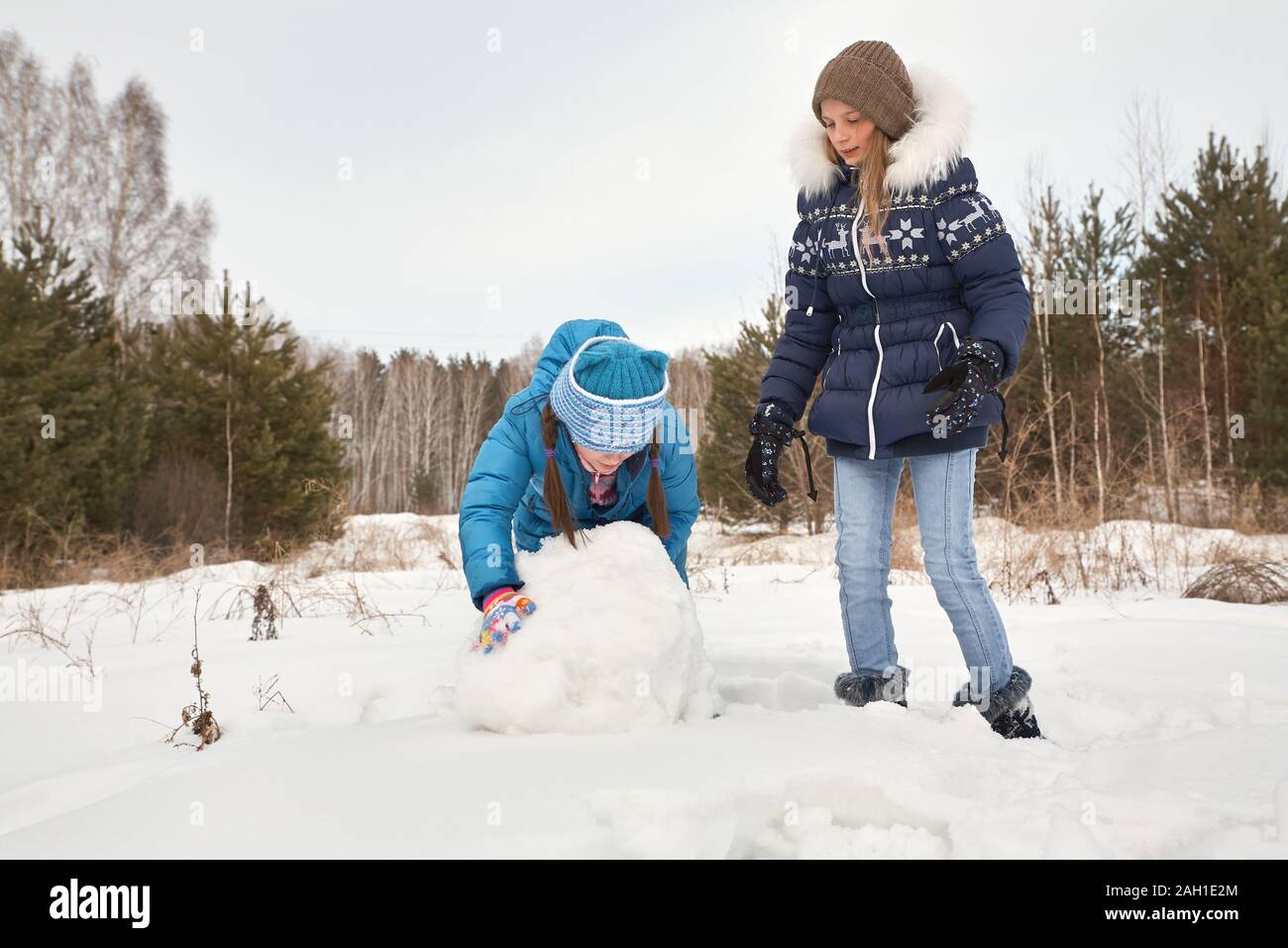 deux amies qui construisent un bonhomme de neige. des filles drôles sur une promenade en plein air en hiver. Banque D'Images