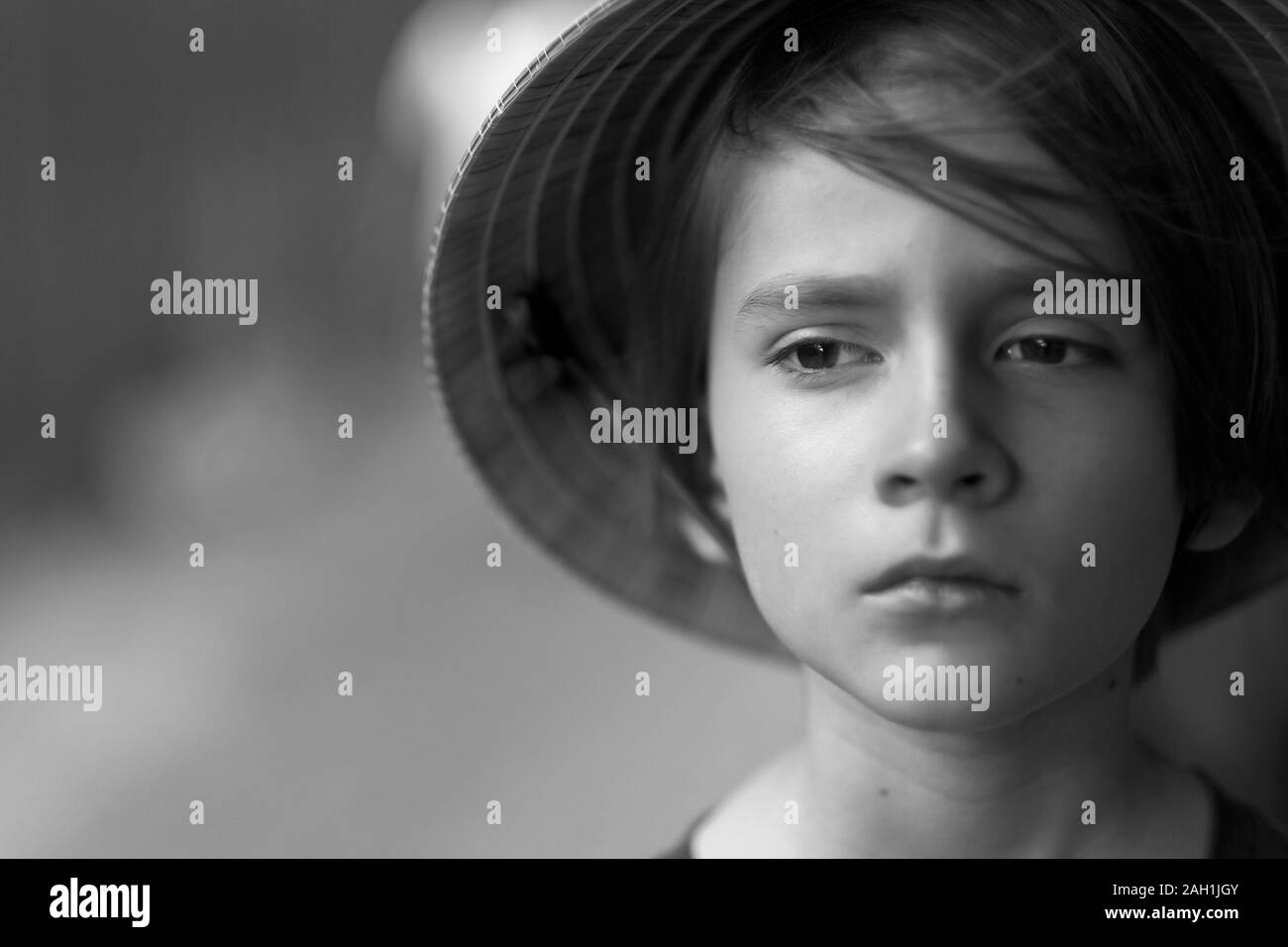 Portrait d'un enfant avec un visage triste dans un chapeau de paille traditionnel vietnamien Banque D'Images