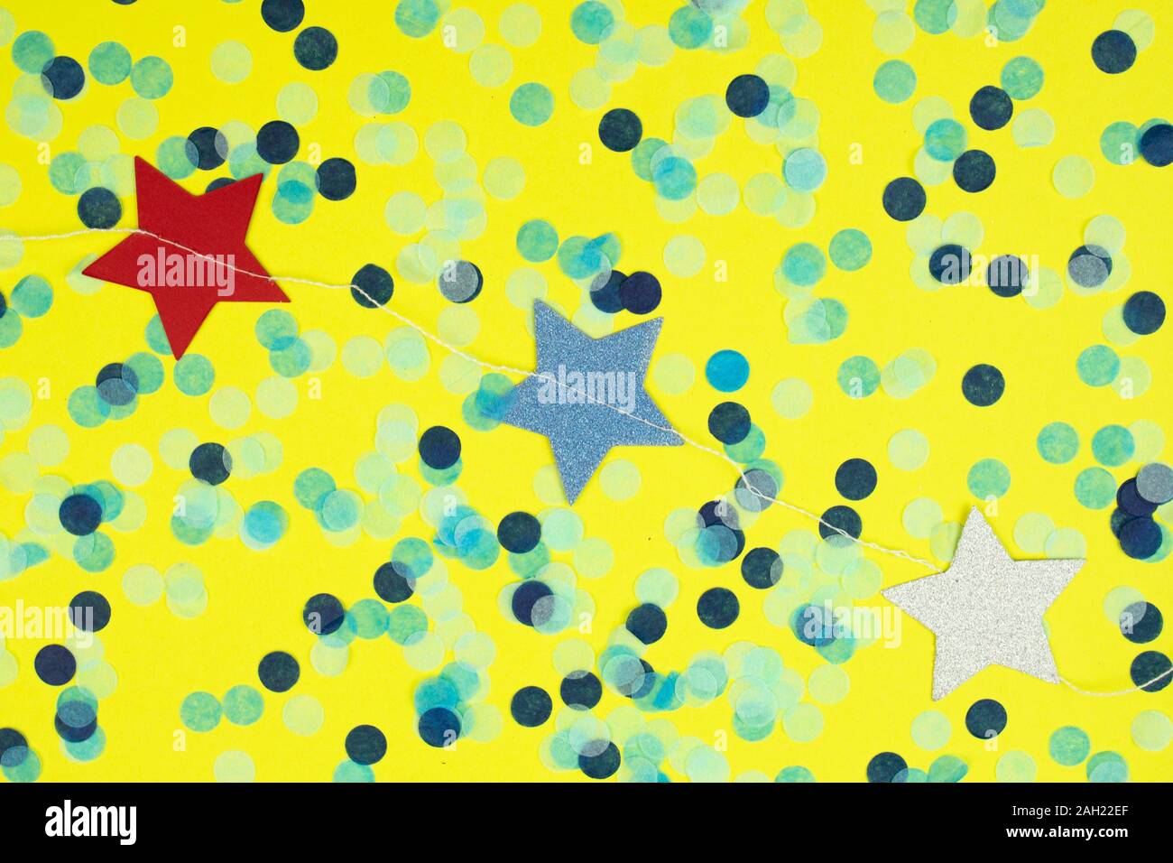 La guirlande d'étoiles colorées et confettis blancs sur fond jaune classique. Banque D'Images