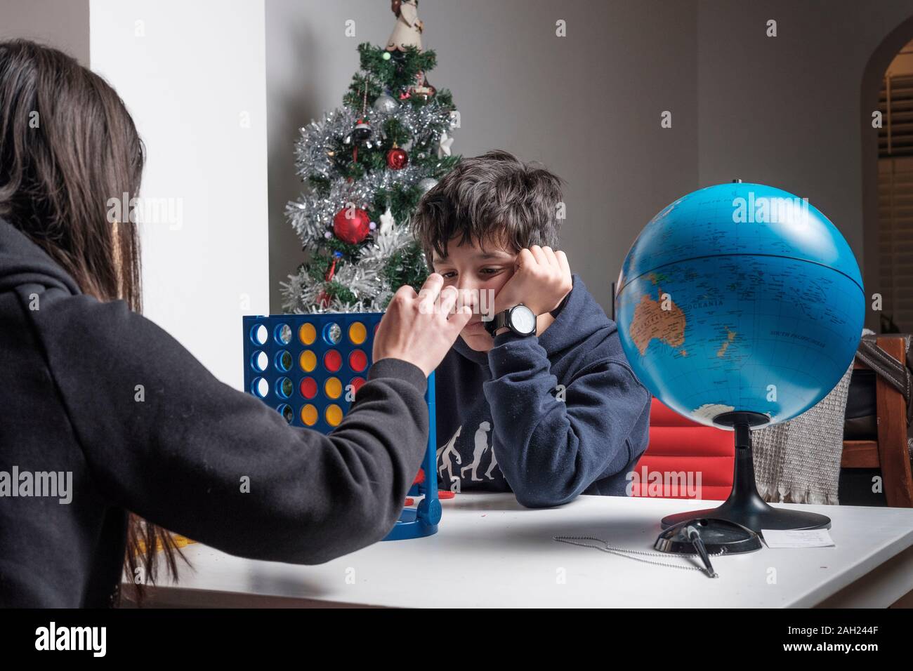 Les frères et sœurs ennuient jouent au jeu Connect four le jour de Noël Banque D'Images